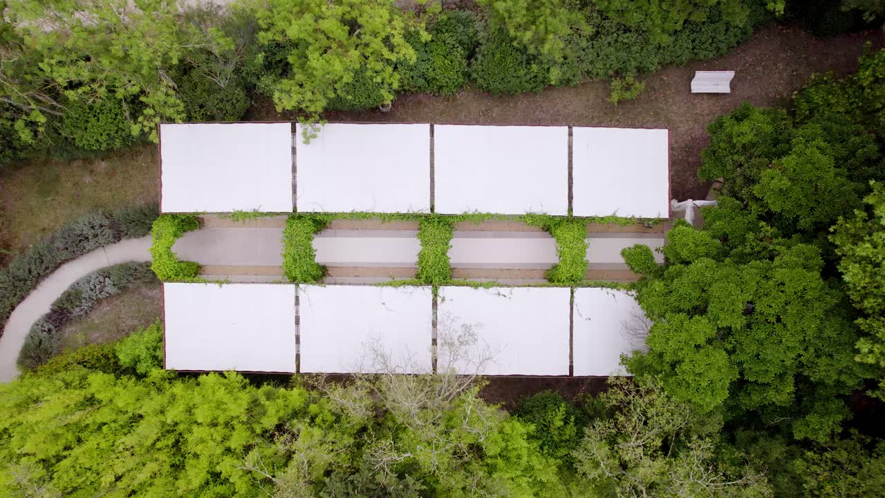 vista aérea de un jardín blanco con arcos de plantas verdes, grandes paneles de tela blanca para protegerse de la lluvia o el sol, ideal para una ceremonia de boda
