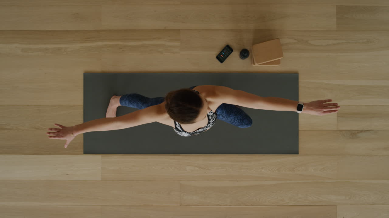 vista superior de una mujer de yoga practicando pose de guerrero en un estudio de ejercicios disfrutando de un estilo de vida saludable, practicando meditación en una colchoneta de ejercicios