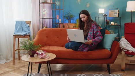 young woman girl freelancer starts working on laptop sends messages makes online purchases at home