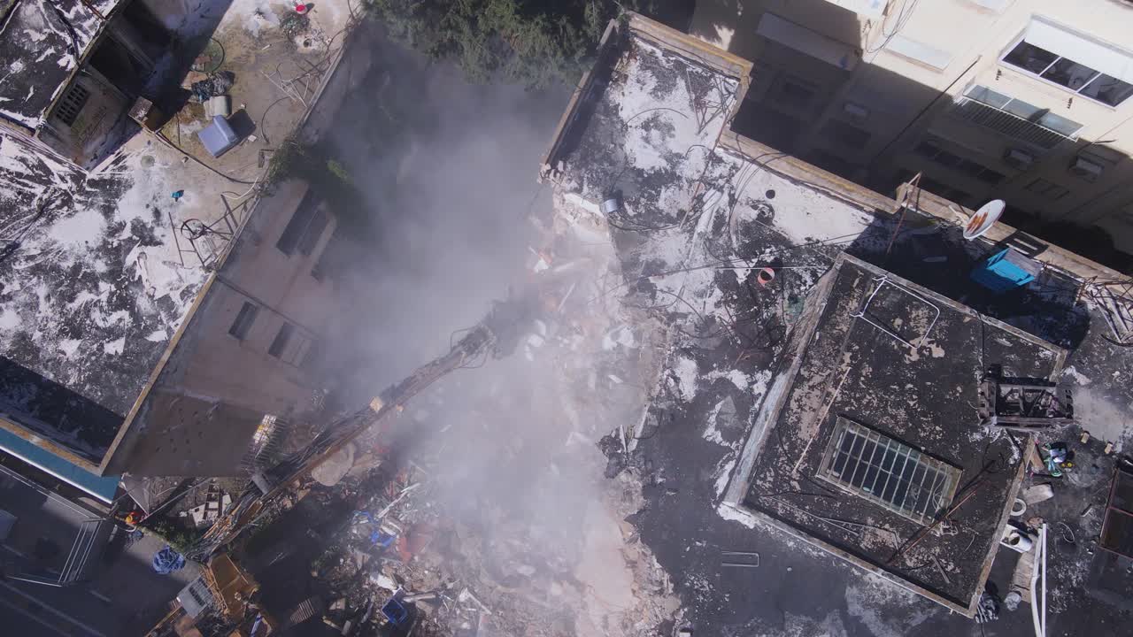 drones de arriba hacia abajo pan por encima de la demolición de edificios con maquinaria pesada en el sitio de construcción