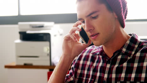 Business-executive-talking-on-mobile-phone-while-working-on-laptop