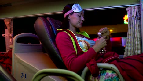 una mujer en el autobús de sueño levanta la parte trasera del asiento y bebe agua de la botella