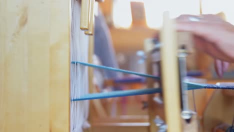 Mid-section-of-old-caucasian-senior-woman-weaving-cloth-on-handloom-machine-in-a-workshop-4k