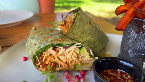 healthy chicken wrap with vegetables, chili flakes and sweet potato fries in marbella spain, enjoying brunch during summer at a restaurant, 4k shot