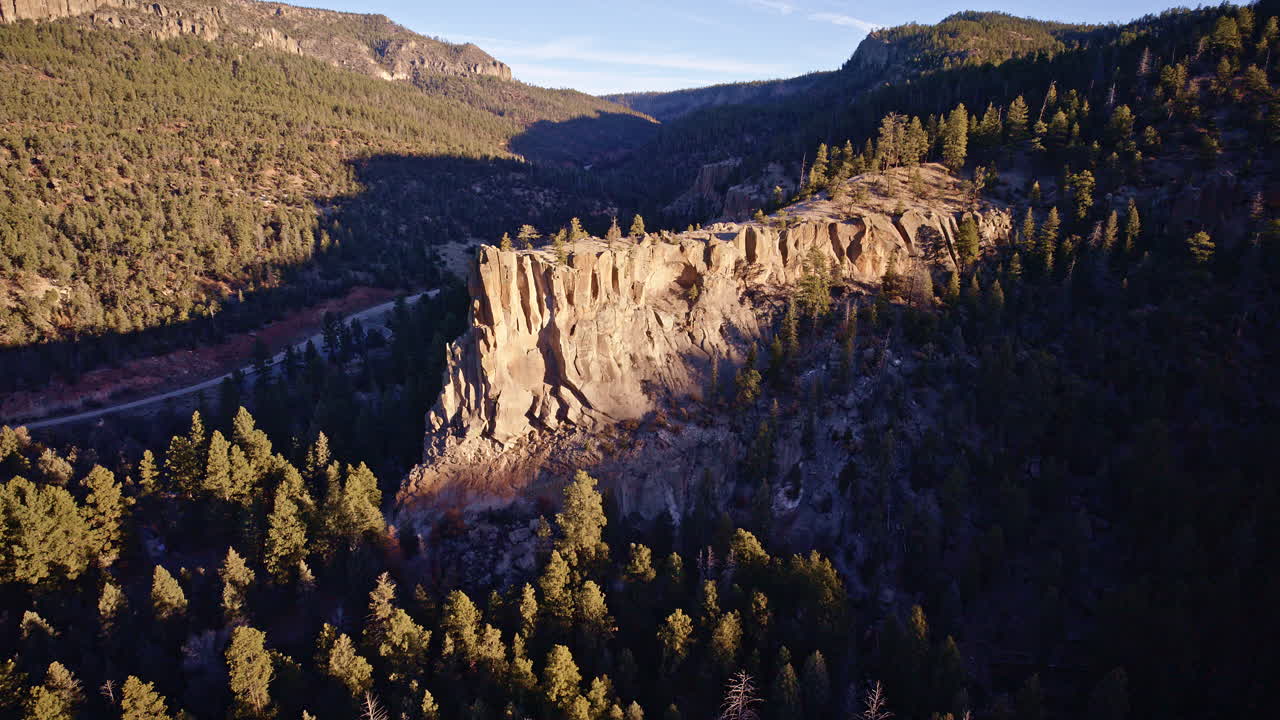 Vista aérea con dron de formaciones de acantilados irregulares con grupos de árboles dispersos en el paisaje desértico de Nuevo México.
