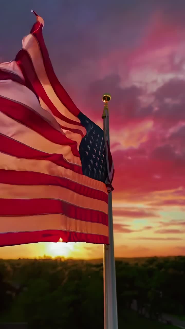 Angolazione aerea del video di una bandiera americana che sventola sullo sfondo di un cielo al tramonto dai colori vivaci, catturando l'orgoglio patriottico