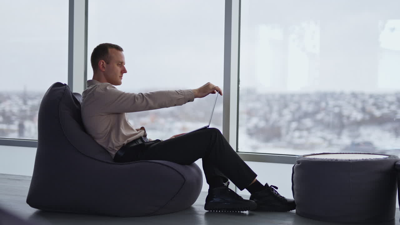 Businessman working on laptop in a modern office with city view