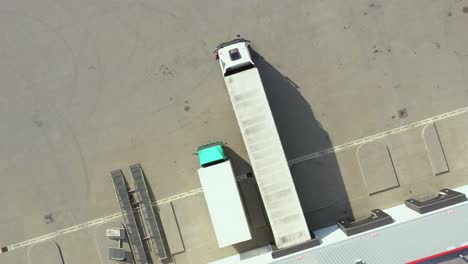 vista aérea de camiones semirremolques parados en las rampas del almacén para cargar y descargar mercancías en el parque logístico