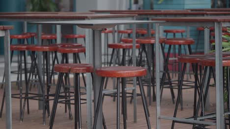 empty tables and bar stools in an outdoor cafe or restaurant setting