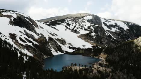 Wide aerial view of Saint Mary&#039;s Glacier looming over a icy cold lake in Colorado