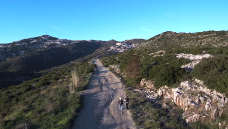 a young couple is walking on a gravel mountain road