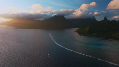 sailboat sunset at moorea island cooks opunohu bay french polynesia aerial drone bright blue lagoon coral reef mount mauaroa tohivea rotui jagged peaks haapiti paopao south pacific ocean circle left