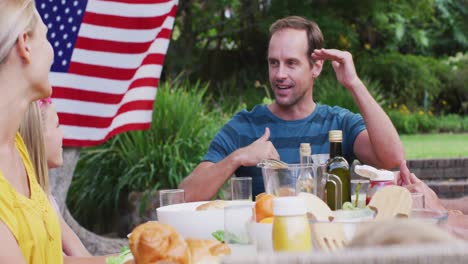 Smiling-caucasian-man-talking-during-family-celebration-meal-in-garden