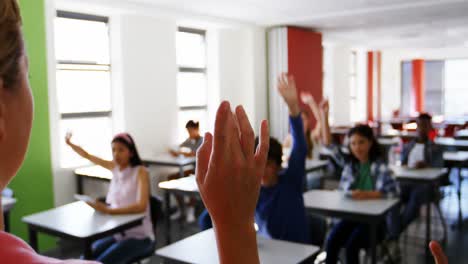 students raising their hands in classroom