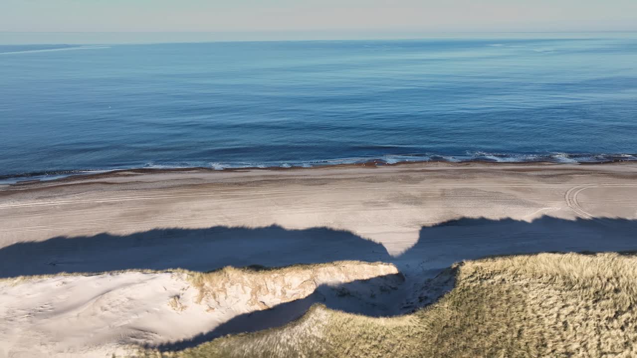 A drone captured stunning footage of a wild beach along the North Sea, where high dunes covered with grass stretch toward the horizon.