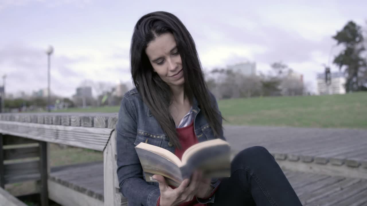 Giovane donna che legge un libro all'aperto in un parco