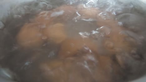 close of up eggs in a pot with hot water at simmer