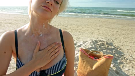 una mujer con piel sensible al calor del sol aplicándose la crema solar en el pecho y disfrutando del tierno toque de sus dedos