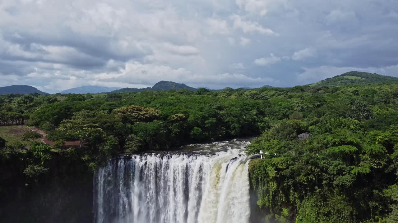 tiro inclinado hacia abajo con una hermosa cascada en la jungla mexicana rodeada de exuberante vegetación en ambos lados con la vista de las colinas en el fondo
