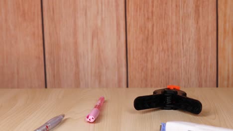 hands manipulate objects on a wooden desk