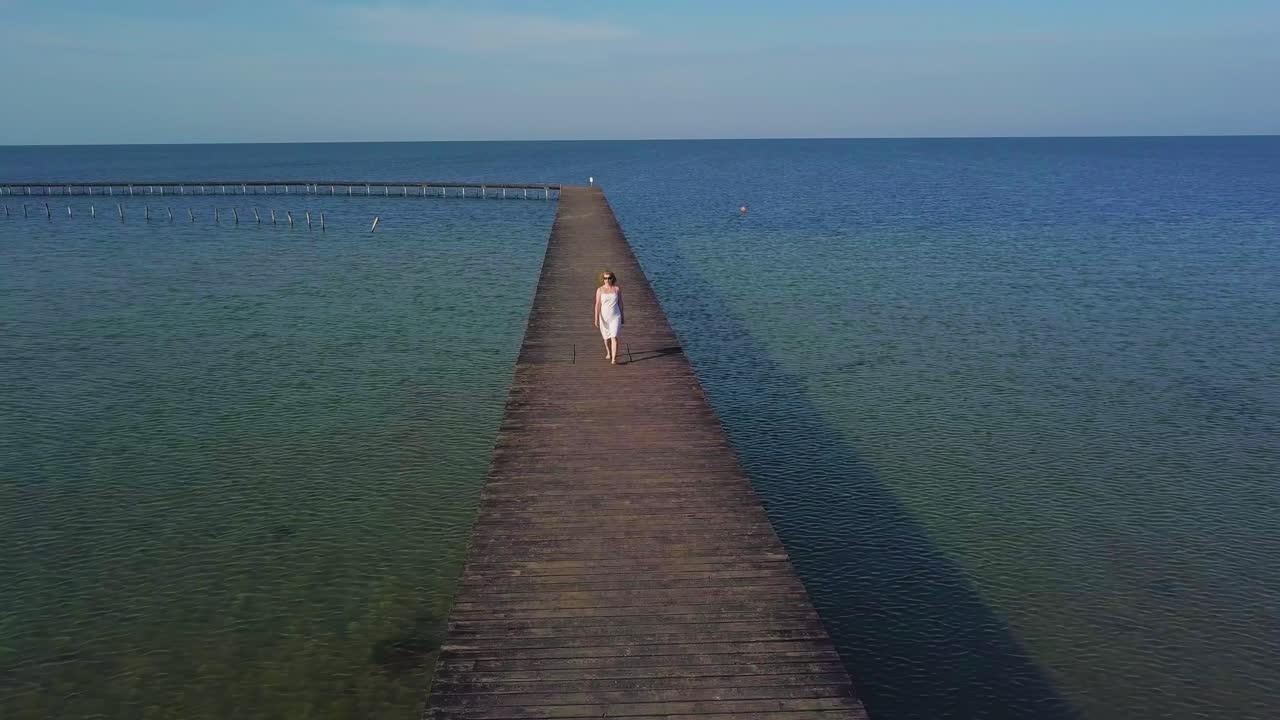 A girl walks on a wooden pier near the sea 04