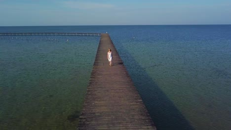 una chica camina en un muelle de madera cerca del mar 04