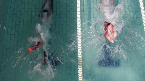 above view of swimmers diving into pool