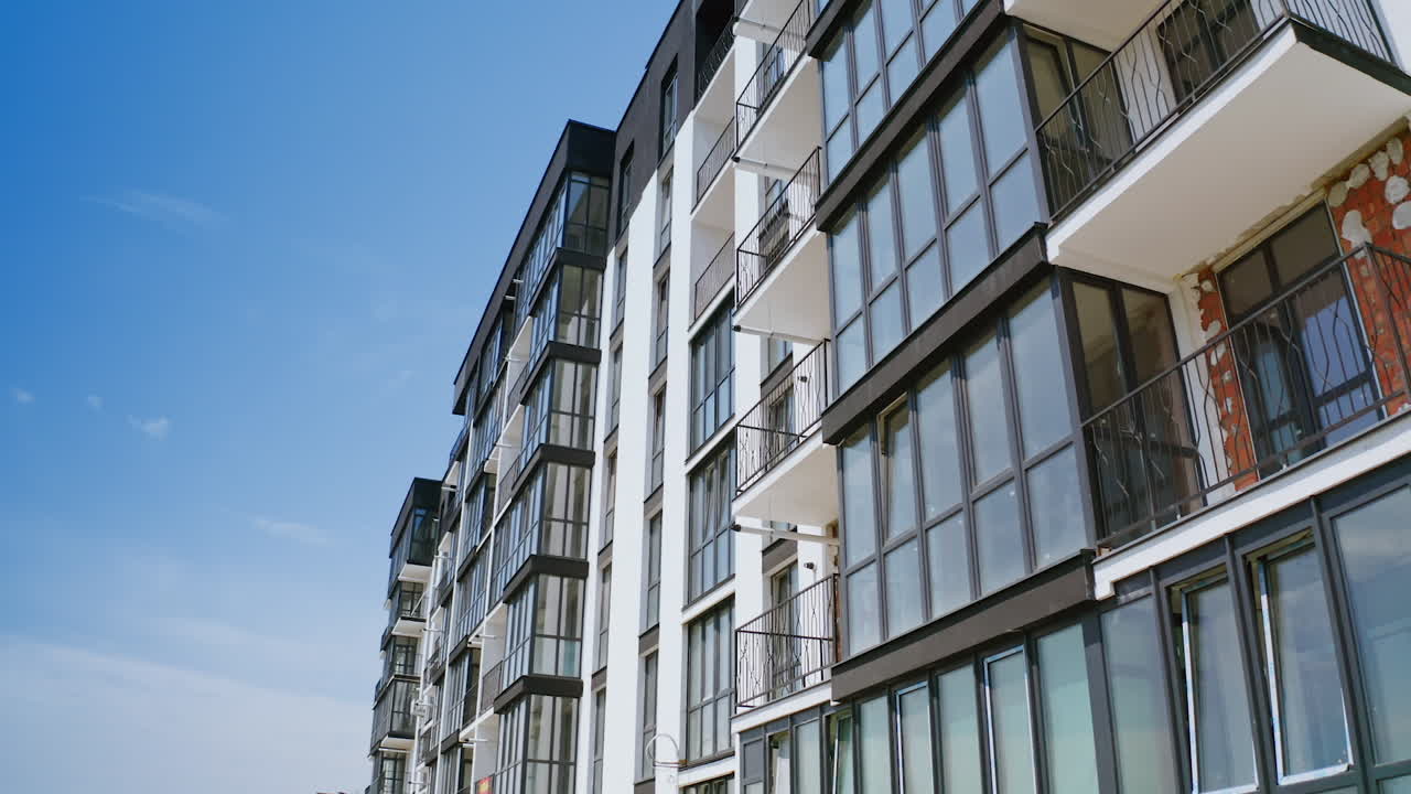 Modern facade of multi-storied-building. New apartment building in black and white colors against blue sky. Drone view.