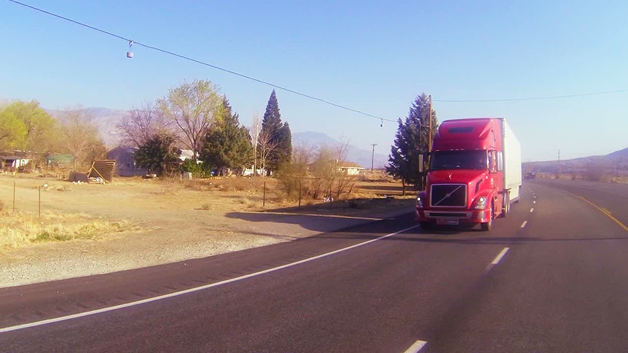 un camión rojo de 18 ruedas se mueve por el desierto en esta toma de punto de vista 1