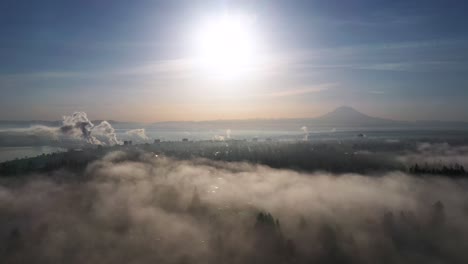 cloud bank with fog overlooking sunrise shining over tacoma in washington state, usa