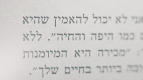 a macro smooth and detailed tilt up shot of a book in hebrew, black letters on white paper, 4k video