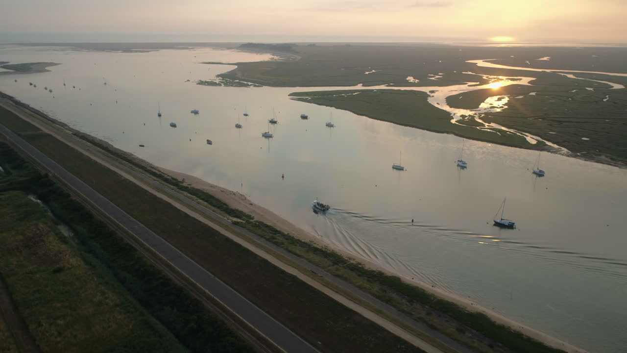 노스 노퍽 영국 동부 해안의 웰스-넥스트-더-시(wells-next-the-sea)에 있는 염습지 물에 반사된 멋진 일출과 함께 항구를 떠나 바다로 향하는 작은 작업용 어선의 드론 샷