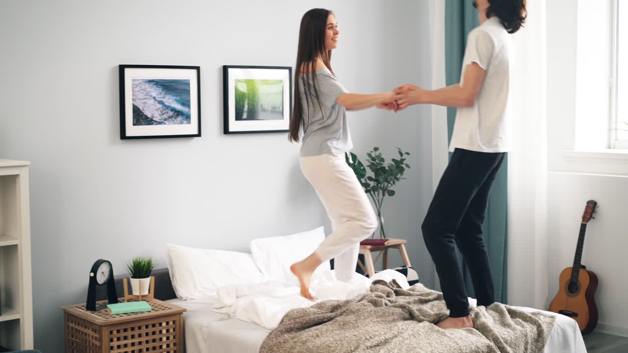 행복한 커플이 침대에서 춤을 춘다