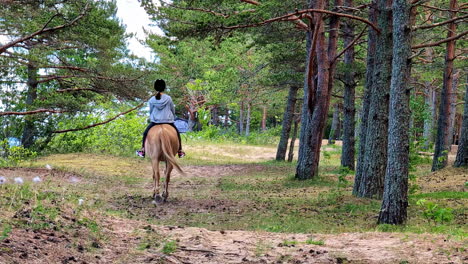 girl horseback riding on a forest trail