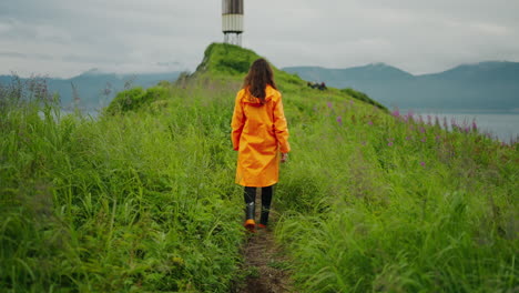 woman in orange raincoat hiking on a coastal path