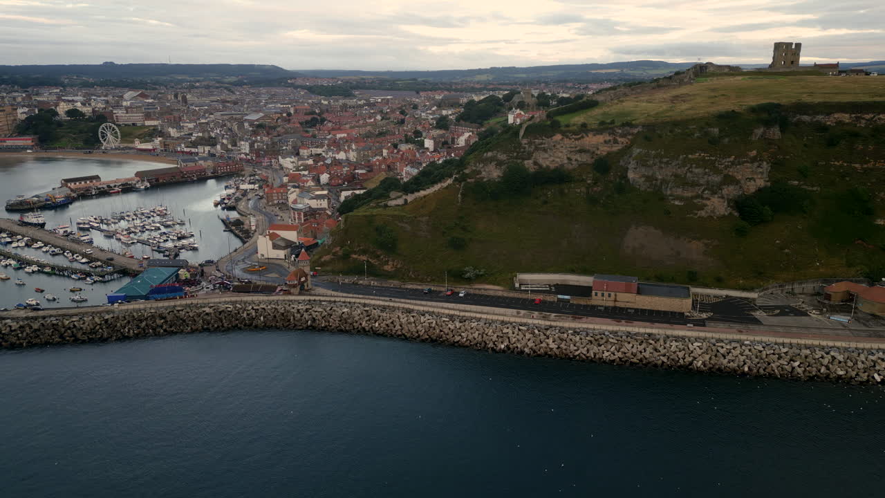Roterande etablerande drönarbild runt Scarborough hamn och slott en mulen morgon
