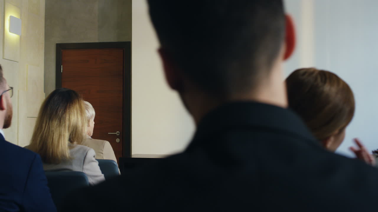 자신감 있고 감정적으로 말하는 백인 사업가의 말을 듣고 있는 회의실에 앉아 있는 사람들의 뒷모습