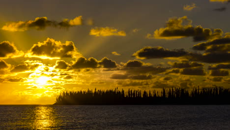 puesta de sol sobre la isla tropical y el océano, a través de nubes de carreras