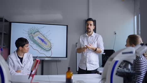 a teacher lectures to students in a science classroom about a bacteria.