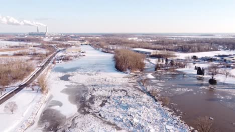 ice jam on the river raisin in monroe city, michigan, usa and visible monroe coal power plant in the background