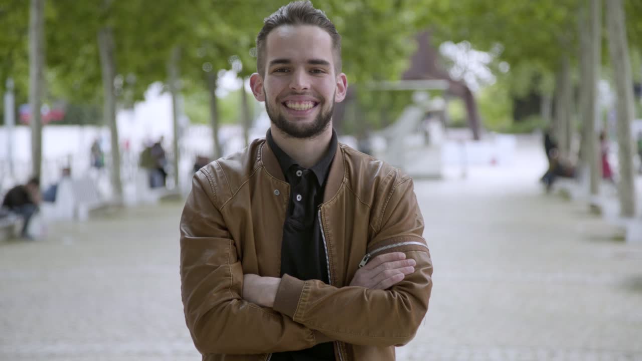 Vista frontale di un giovane uomo sorridente con le braccia incrociate.