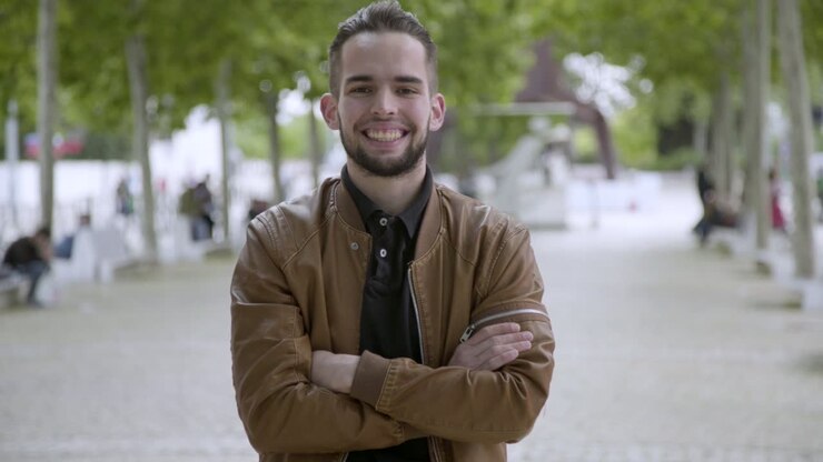 Vista frontale di un giovane uomo sorridente con le braccia incrociate.