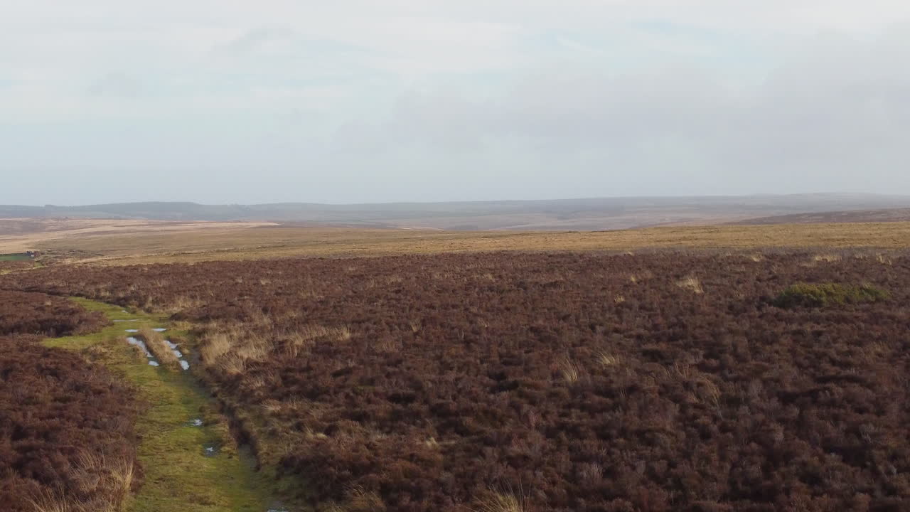 atleta de fitness corredor tiro de seguimiento aéreo que se eleva para revelar el paisaje rural en exmoor - tiro de drone uk 4k