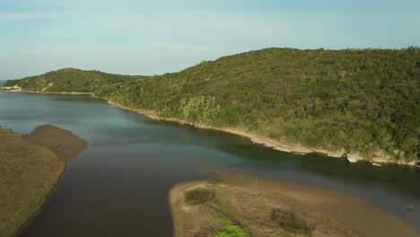 Aerial-flying-forward-river-stream,-river-island-surrounded-by-green-hills