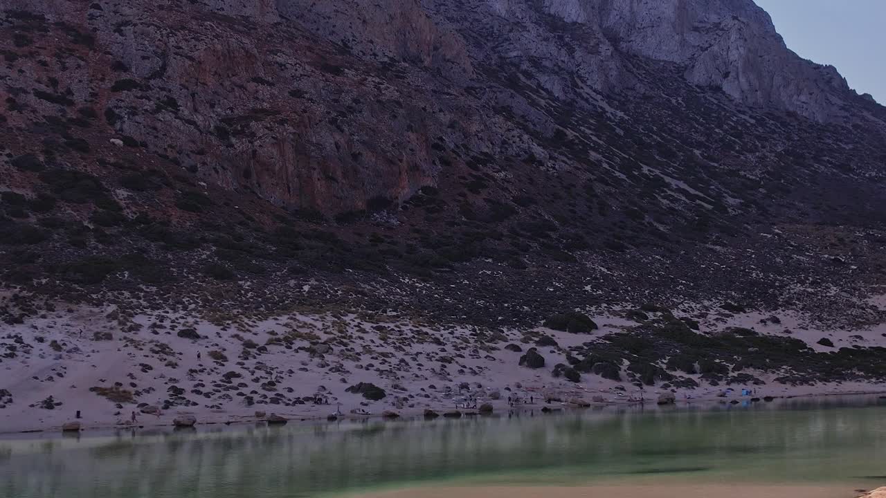 Luftfoto af en rolig strand med Rocky Mountains og klart vand