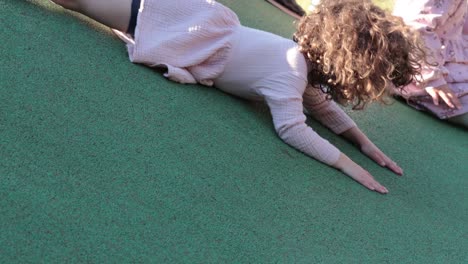 una niña deslizándose por una colina de un patio de recreo