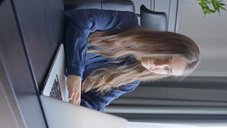 Young-female-working-in-domestic-environment-with-laptop,-vertical-view