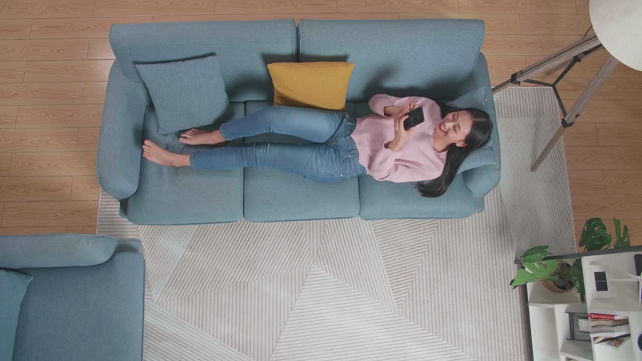 mujer relajándose en el sofá y usando el teléfono inteligente