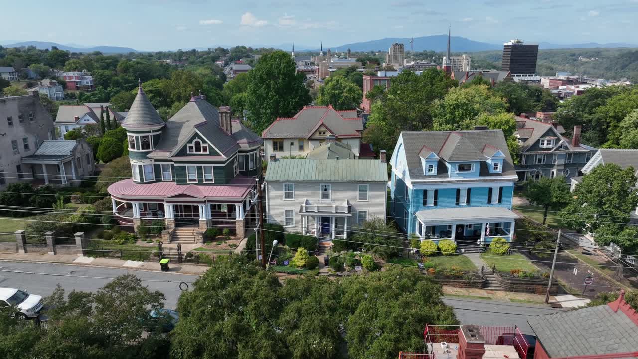 Historic colored facade of Victorian houses and villas in american residential area. Aerial approaching shot. Sunny summer day with downtown in background