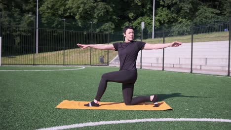 a fit woman performs an exercise routine on a yoga mat placed on a soccer field under bright a fit woman performs an exercise routine on a yoga mat placed on a soccer field under bright sunlight promoting wellness and active lifestyle